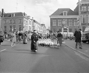 880566 Afbeelding van het drijven van een koppel ganzen door enkele Drentse ganzenhoedsters door de Voorstraat te ...